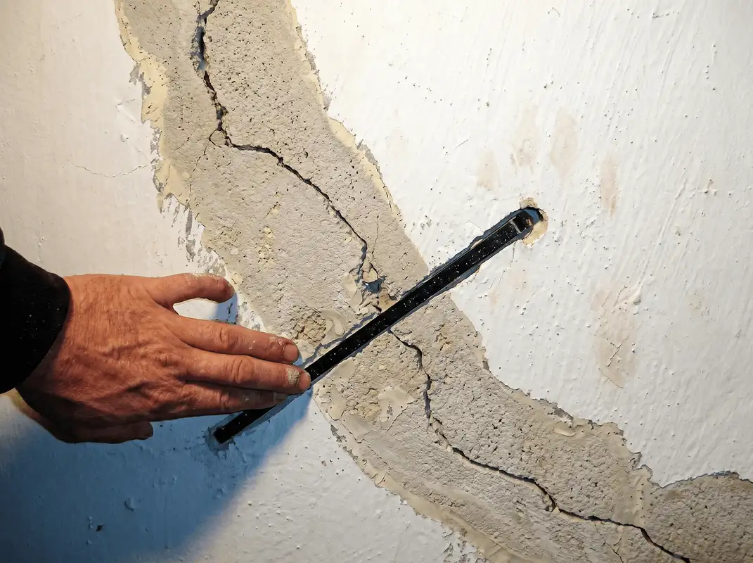 A wall with a large crack is being inspected by a professional in Spokane, WA
